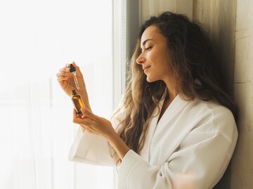 Entspannte Frau im Bademantel mit Serum in der Hand | © GettyImages/Anastasiia Krivenok