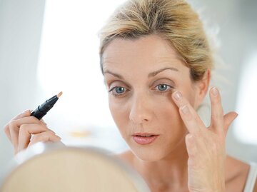 Frau mittleren Alters schminkt sich mit Concealer. | © Adobe Stock/goodluz
