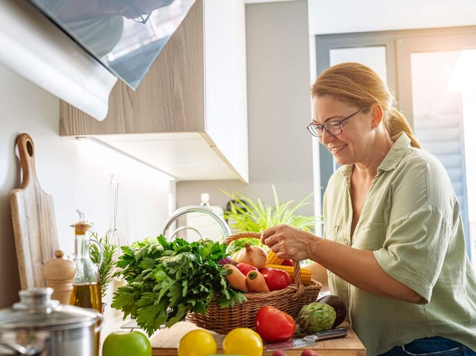 Person mit Gemüse in Küche | © Getty Images/fcafotodigital