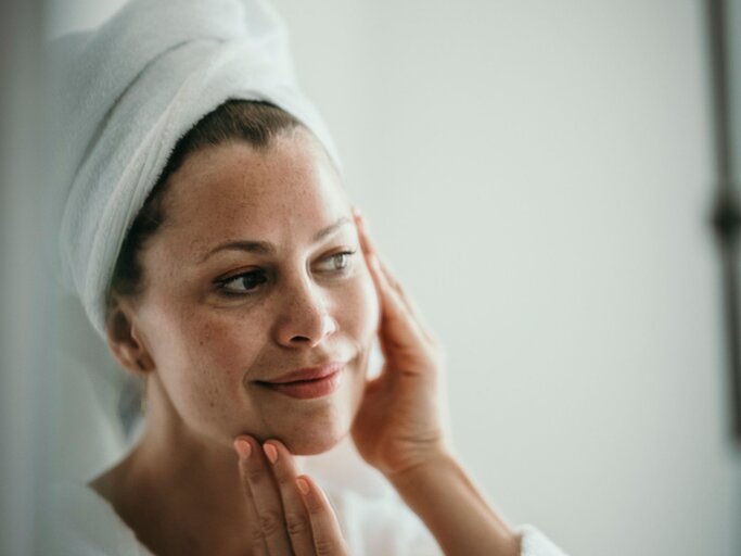 Eine Frau betrachtet nach dem Duschen ihre Haut im Spiegel | © Getty Images / Westend61