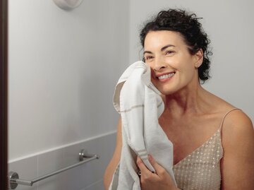 Eine Frau steht im Badezimmer und reinigt sich ihr trockenes Gesicht | © Getty Images / Eva-Katalin
