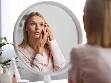 Frau sieht sich im Spiegel an | © Adobe Stock/Prostock-studio
