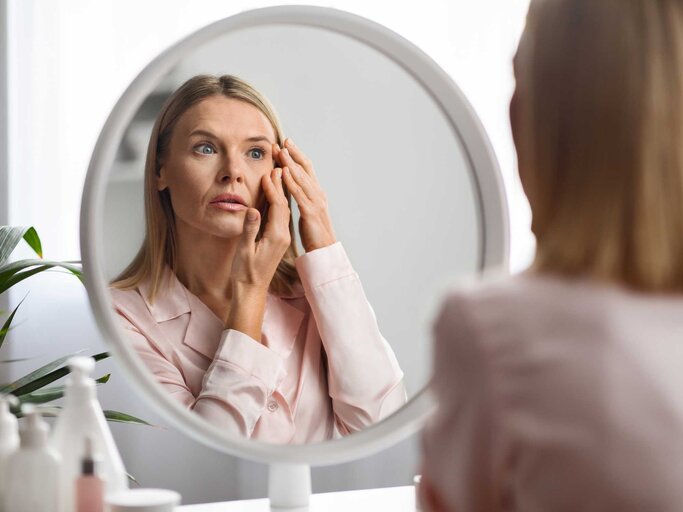 Frau sieht sich im Spiegel an | © Adobe Stock/Prostock-studio