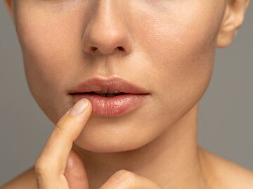 Frau fasst sich mit Finger an trockene Lippe | © AdobeStock/DimaBerlin