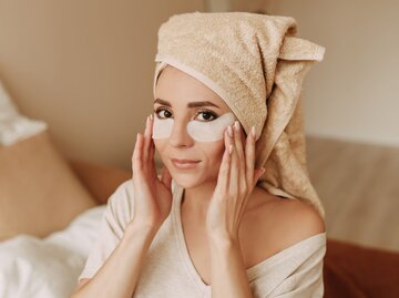 Porträt einer Frau mit Handtuchturban auf dem Kopf und Eyepatches auf dem Gesicht | © Getty Images / Elizaveta Starkova