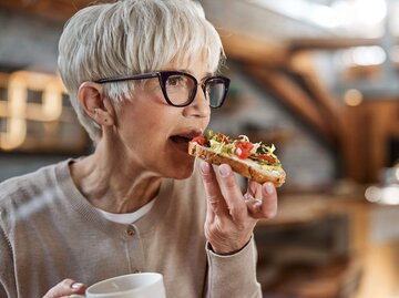 Person beißt in belegtes Brot | © Getty Images/skynesher