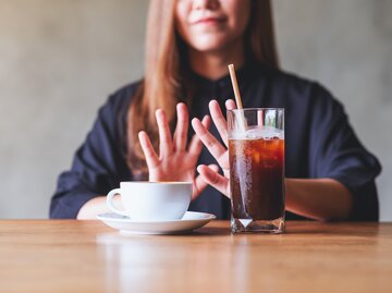 Eine Frau hebt ihre Hände abwehrend gegen Kaffee | © GettyImages/Farknot_Architect