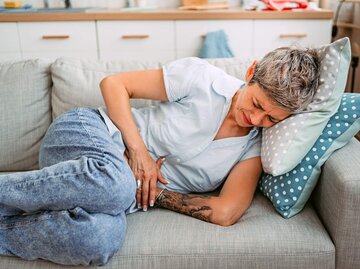 Person mit Magenschmerzen auf der Couch | © Getty Images/urbazon