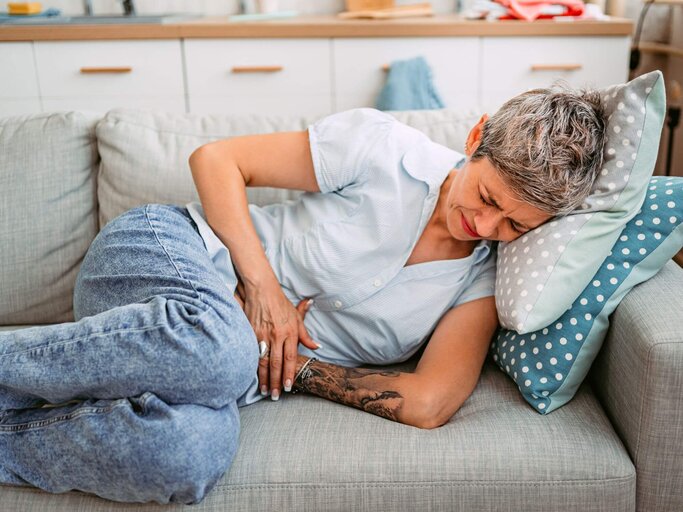 Person mit Magenschmerzen auf der Couch | © Getty Images/urbazon