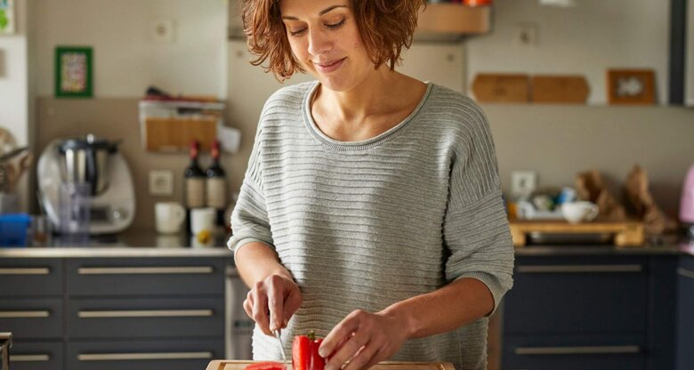 Person in Küche schneidet Tomate | © Getty Images/Westend61