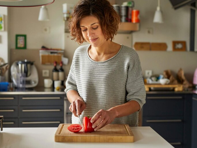 Person in Küche schneidet Tomate | © Getty Images/Westend61