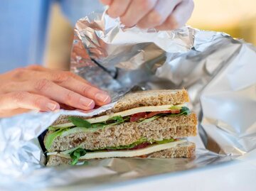 Frau wickelt Sandwich in Alufolie | © Getty Images/Daisy-Daisy