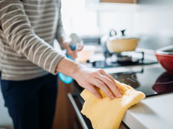 Frau putzt die Küche mit einem Waschlappen | © Getty Images/d3sign
