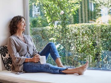 Frau sitzt am Fenster | © Getty Images/Oliver Rossi