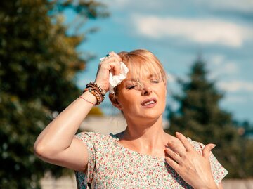 Einer Frau ist heiß und sie tupft sich die Stirn ab | © GettyImages/Biserka Stojanovic