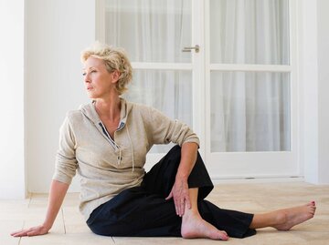 sportliche Frau, die zu Hause Yoga praktiziert und die Pose des halben Herrn der Fische macht. Ardha Matsyendrasana. | © Getty Images / PhotoAlto/Frederic Cirou