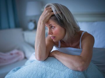 Frau sitzt im Bett und rauft sich die grauen Haare | © Getty Images/Tetra Images