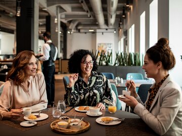 Drei Personen in Restaurant beim Frühstücken | © Getty Images/Marko Geber