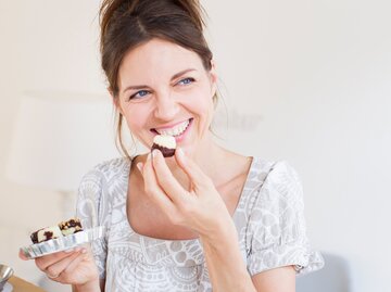 Eine Frau isst kleine Energiebällchen, die eine gesündere Alternative zu Kuchen und Co. sind | © GettyImages/Streetangel