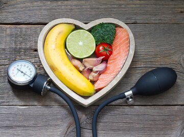 Blutdruckmessgerät mit herzförmiger Schale gefüllt mit Lebensmitteln | © Getty Images/udra