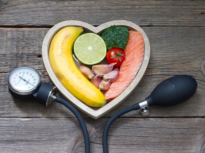 Blutdruckmessgerät mit herzförmiger Schale gefüllt mit Lebensmitteln | © Getty Images/udra