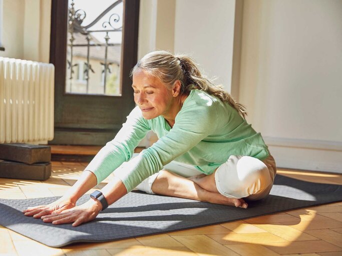 Ältere Frau macht Dehnübungen auf einer Yogamatte | © Getty Images/Westend61