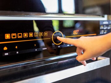 Person bedient Backofen per Touchscreen | © Getty Images/owngarden