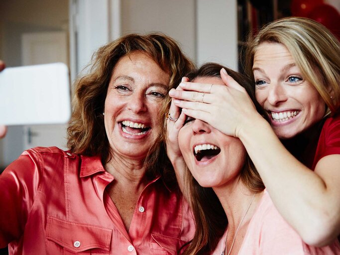 Drei Freundinnen machen zusammen lachende ein Selfie. | © Getty Images/Silke Woweries