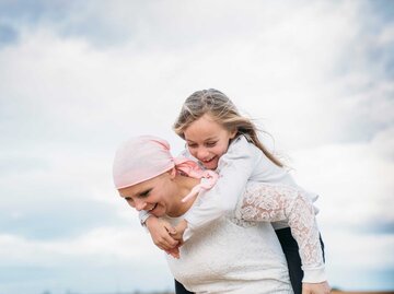 Frau mit Kind auf dem Rücken und rosa Kopftuch | © Adobe Stock/karrastock