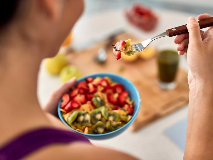 Frau frühstückt eine Bowl mit verschiedenem Obst. | © Adobe Stock/Drazen