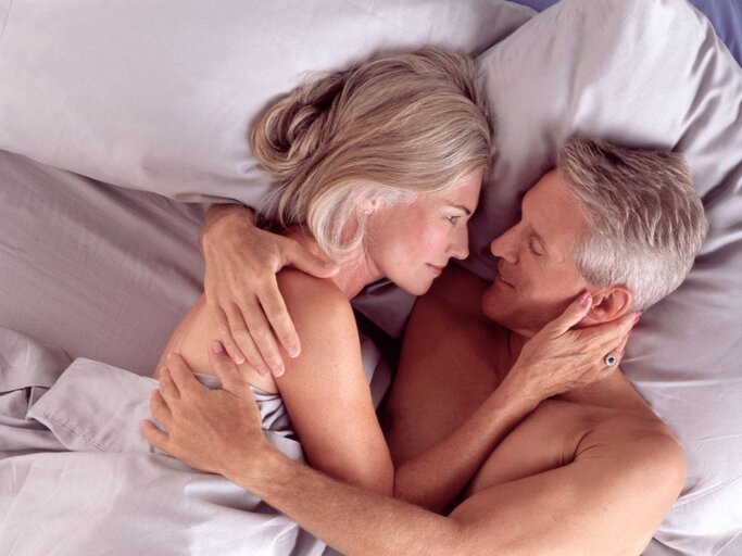 Ein Paar um die 50 liegt gemeinsam im Bett | © Getty Images / Larry Williams