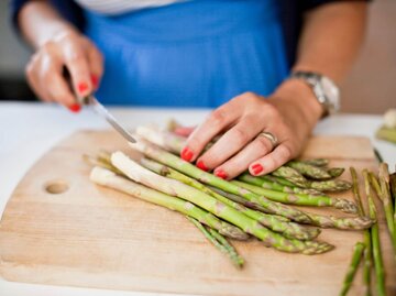 Frau schneidet grünen Spargel | © Getty Images/Maskot