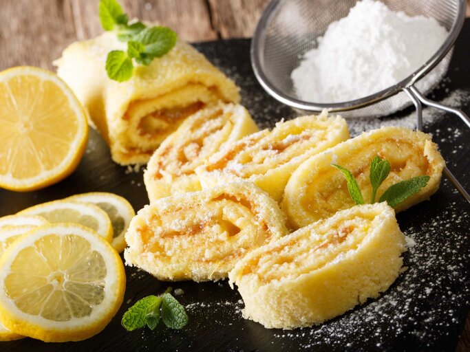 Hausgemachter Zitronenkuchen mit Fruchtcreme, dekoriert mit Minze und Puderzucker | © Getty Images/ALLEKO