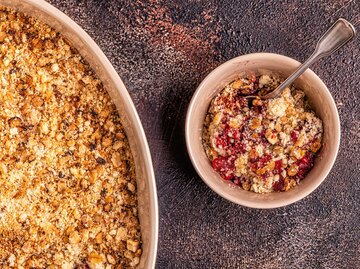 Eine Schale Crumble auf einem Holztisch, Fotografie von oben | © Getty Images/tbralnina