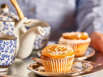 Nahaufnahme von einem Silbertablett mit einem Jaffa Cupcake, Teetasse und Teekanne | © Getty Images/Westend61