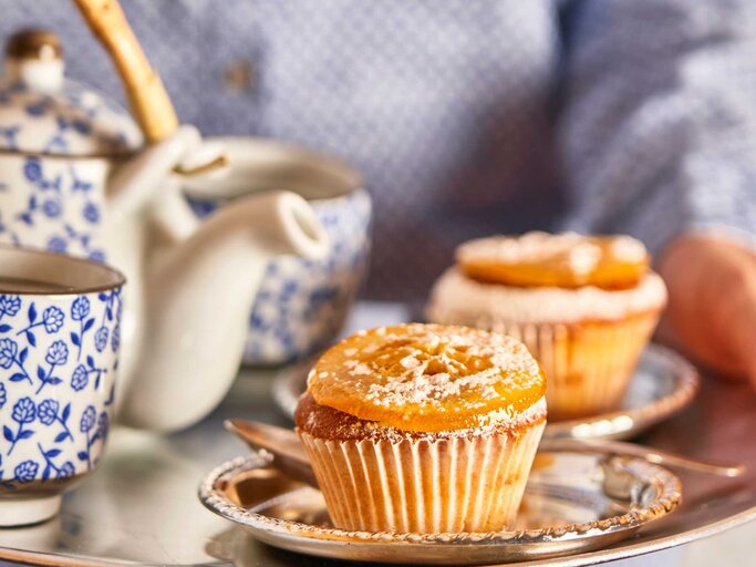 Nahaufnahme von einem Silbertablett mit einem Jaffa Cupcake, Teetasse und Teekanne | © Getty Images/Westend61