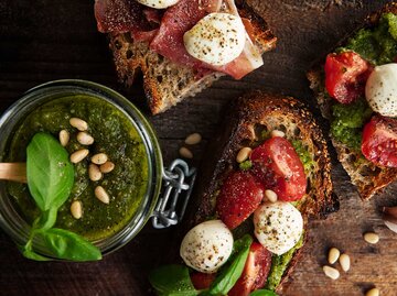 Frisches Bruschetta mit Pestosauce, Tomaten, Mozzarella und Schinken,  Ansicht von oben  | © Getty Images/Monica Bertolazzi