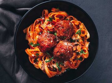 Spaghetti mit Hackbällchen auf schwarzem Hintergrund im schwarzen Teller | © Getty Images/Cris Cantón