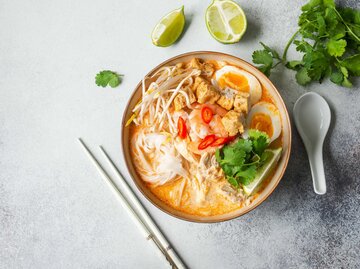 Laksa-Suppe mit Huhn, Garnele und Tofu in einer Schüssel auf grauem Hintergrund | © Adobe Stock/senteliaolga
