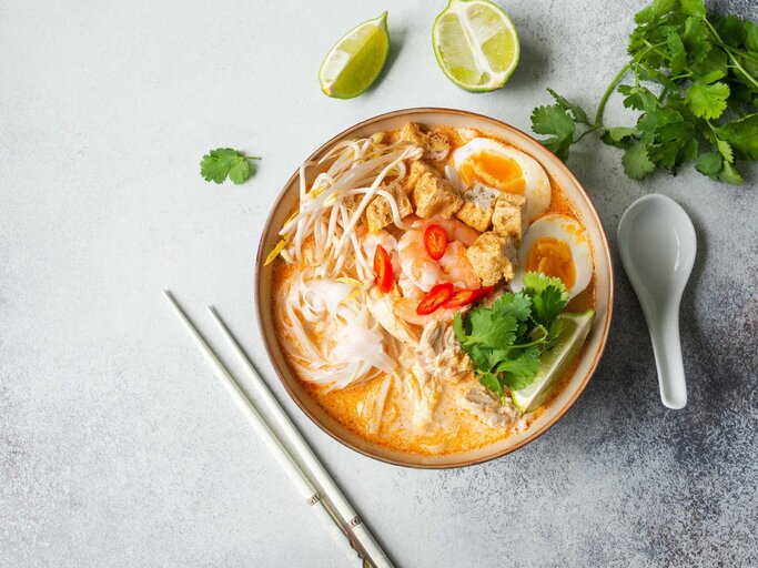 Laksa-Suppe mit Huhn, Garnele und Tofu in einer Schüssel auf grauem Hintergrund | © Adobe Stock/senteliaolga
