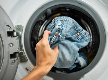 Frau steckt Jeans in die Waschmaschine | © Getty Images/Wachiwit