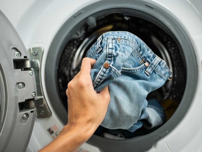 Frau steckt Jeans in die Waschmaschine | © Getty Images/Wachiwit