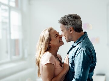 Eine Frau und ein Mann umarmen sich und grinsen sich an | © GettyImages/Westend61