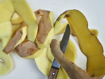Kartoffelschalen mit einem Messer | © Getty Images/annick vanderschelden photography