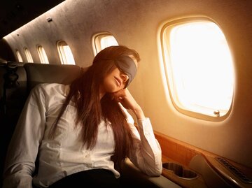 Frau mit Schlafmaske in einem Flugzeug | © Getty Images/Colin Anderson Productions pty ltd