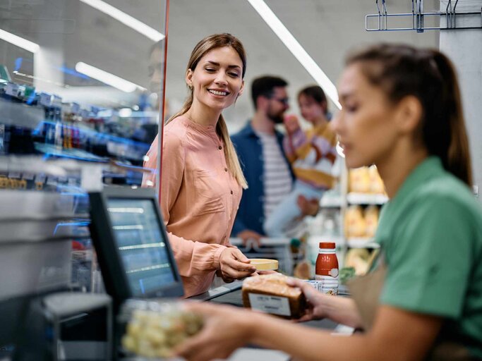 Frau, die Lebensmittel an die Kasse im Supermarkt stellt | © Getty Images/Drazen Zigic