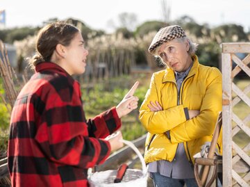 Zwei Nachbarinnen diskutieren am Gartenzaun | © Getty Images/JackF