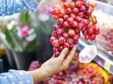 Eine Hand hält Weintrauben im Supermarkt | © Getty Images/ipopba