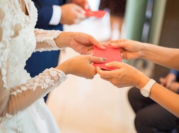 Person übergibt Umschlag an Braut | © Getty Images/hxyume