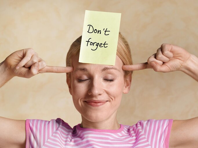 Frau mit "Don't forget"-Post-it auf der Stirn | © Getty Images/Peter Dazeley